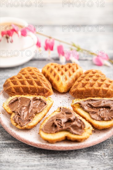 Homemade waffle with chocolate butter and cup of coffee on a gray wooden background. side view,