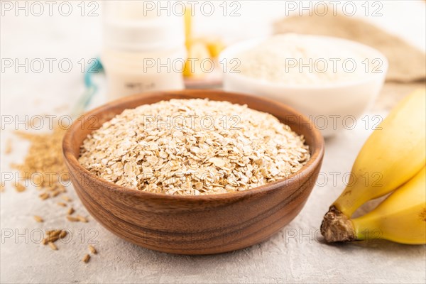 Powdered milk and oatmeal, banana baby food mix, infant formula, pacifier, bottle, spoon on gray