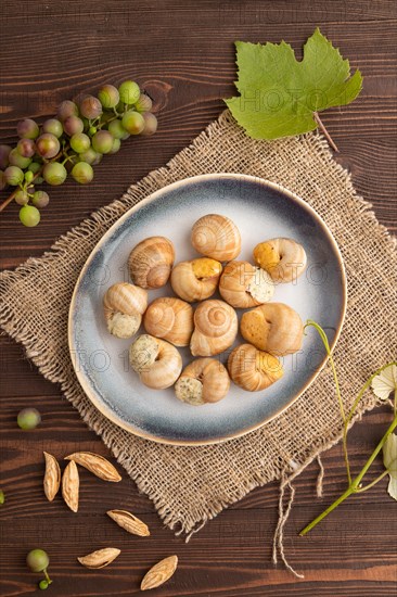 Grape (Burgundy) snails with butter and cheese on brown wooden background and linen textile. Top