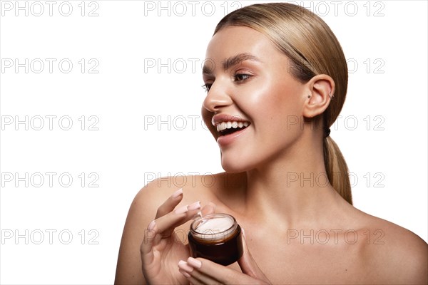 Beauty portrait of model with natural make-up holding a jar of cream. Fashion shiny highlighter on