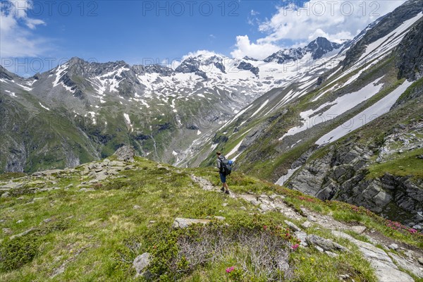 Mountaineer on hiking trail in picturesque mountain landscape, in the background mountain peak