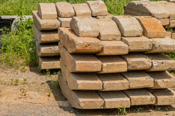 Curved concrete bricks used to support large utility poles stacked in rural countryside