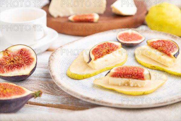 Summer appetizer with pear, cottage cheese, figs and honey on a white wooden background and linen