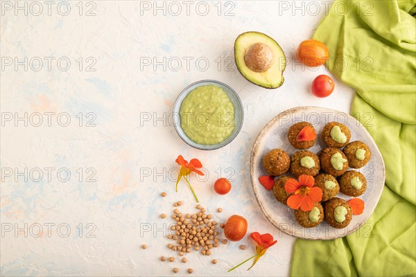 Falafel with guacamole on white concrete background and green linen textile. Top view, flat lay,