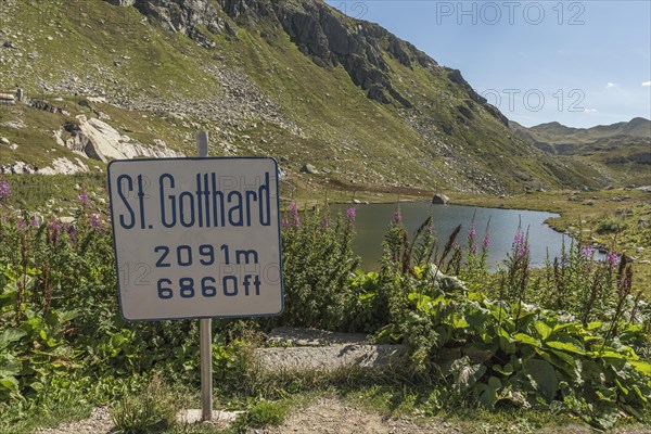 Gotthard Pass, mountain lake and sign with altitude information at the top of the pass, Canton
