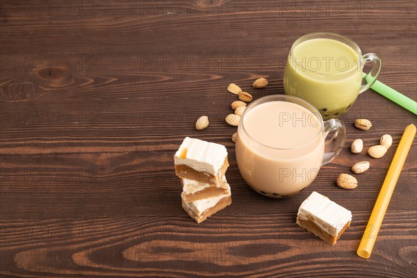 Bubble tea with pistachio and caramel in glass on brown wooden background. Healthy drink concept.