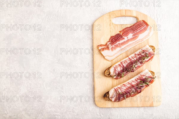 Bread sandwiches with jerky salted meat and lard with beet microgreen on gray concrete background.