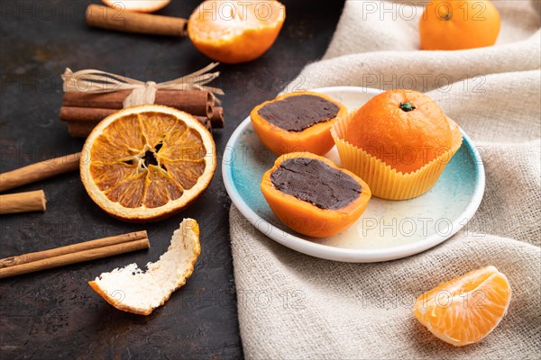 Truffle chocolate tangerine candies on a black concrete background and linen textile. Side view,