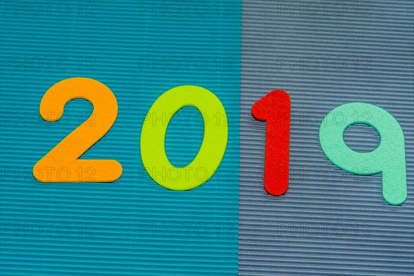 The numbers 2019 made of felt of different colors photographed on blue and maroon corrugated