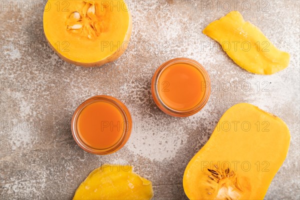 Baby puree with fruits mix, pumpkin, persimmon, mango infant formula in glass jar on brown concrete