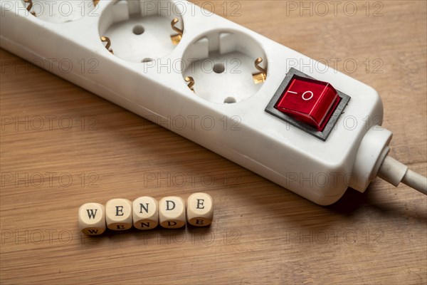 Concept image energy turnaround, switchable socket strip on wooden floor, letter cubes form the