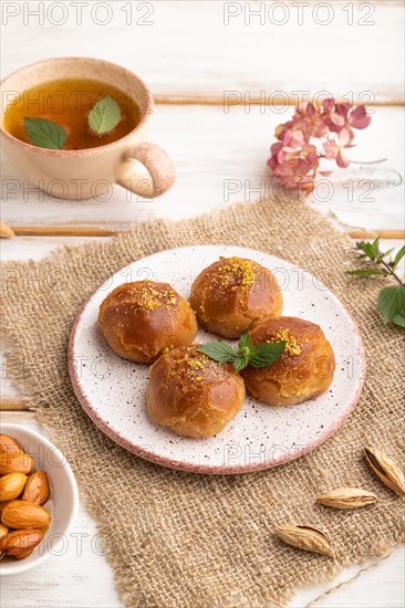 Homemade traditional turkish dessert sekerpare with almonds and honey, cup of green tea on white
