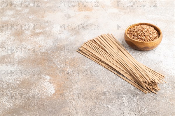 Japanese buckwheat soba noodles with tomato, eggs, spices, herbs on brown concrete background. Side