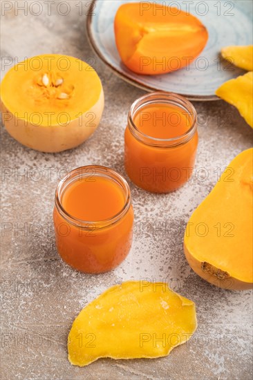 Baby puree with fruits mix, pumpkin, persimmon, mango infant formula in glass jar on brown concrete