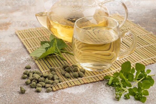 Green oolong tea with herbs in glass on brown concrete background. Healthy drink concept. Side