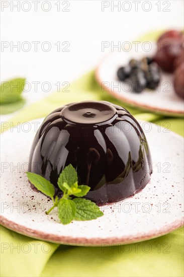 Black currant and grapes jelly on gray concrete background and green linen textile. side view,