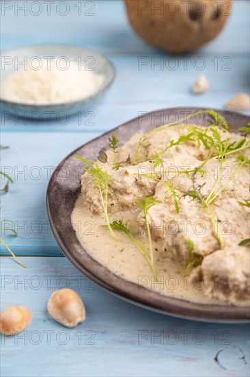 Stewed chicken fillets with coconut milk sauce and mizuna cabbage microgreen on blue wooden