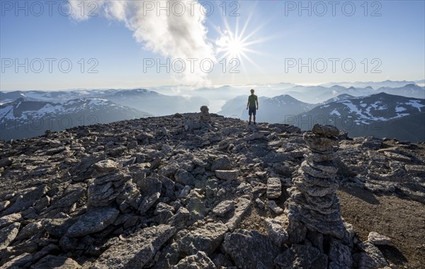Mountaineer on the summit of Skala with cairn, view of mountain landscape and fjord Faleidfjorden,