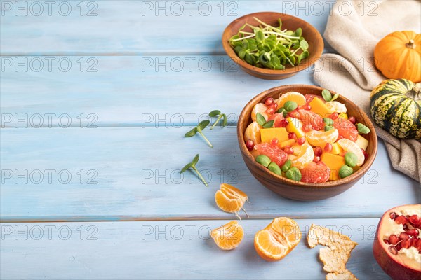 Vegetarian fruit salad of pumpkin, tangerine, pomegranate, grapefruit, sunflower microgreen sprouts