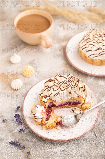 Two tartlets with meringue cream and cup of coffee on brown concrete background. side view,
