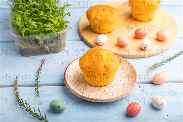 Homemade cakes with chocolate eggs and chrysanthemum microgreen on a blue wooden background. side