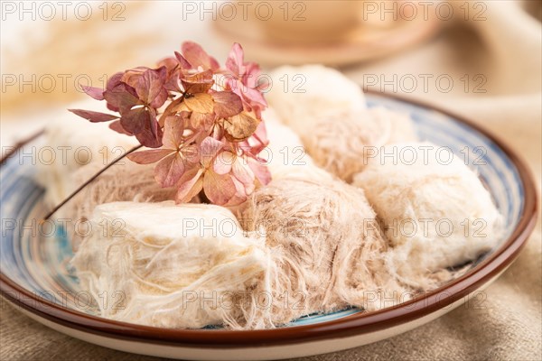 Traditional arabic sweets pishmanie and a cup of green tea on white wooden background and linen