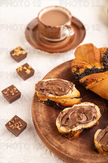 Homemade sweet bun with chocolate cream and cup of coffee on a gray concrete background and linen
