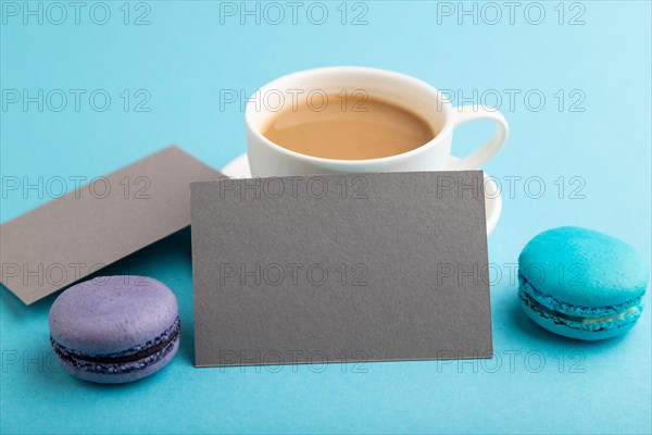 Gray paper business card mockup with blue and violet macaroons and cup of coffee on blue pastel
