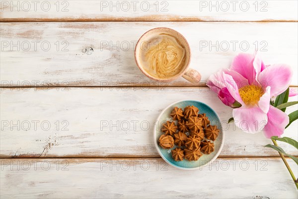 Homemade soft caramel fudge candies on blue plate and cup of coffee on white wooden background,
