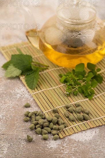 Green oolong tea with herbs in glass on brown concrete background. Healthy drink concept. Side