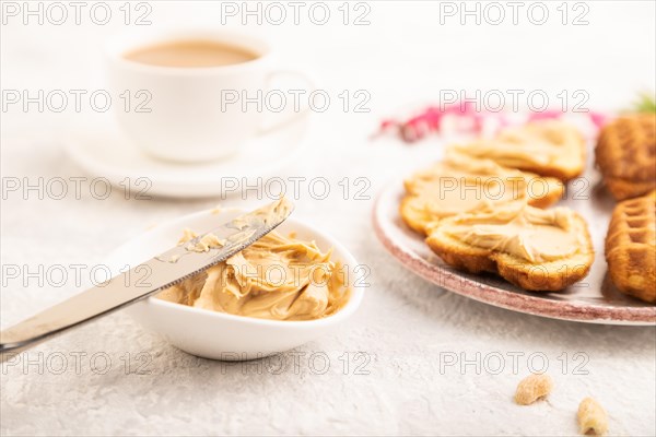 Homemade waffle with peanut butter and cup of coffee on a gray concrete background. side view,