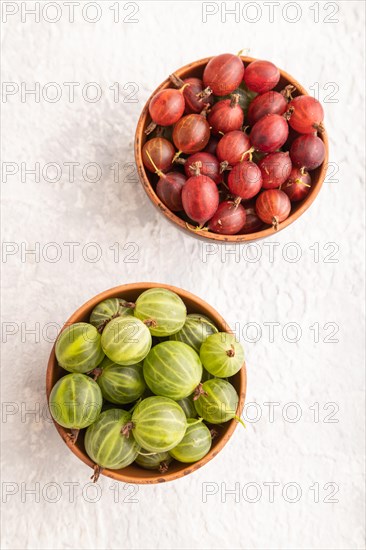 Fresh red and green gooseberry in clay bowl on gray concrete background. top view, flat lay, close