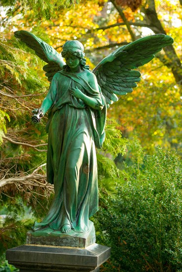 Female angel figure with rose, surrounded by autumnal colours, radiates peace, bronze with