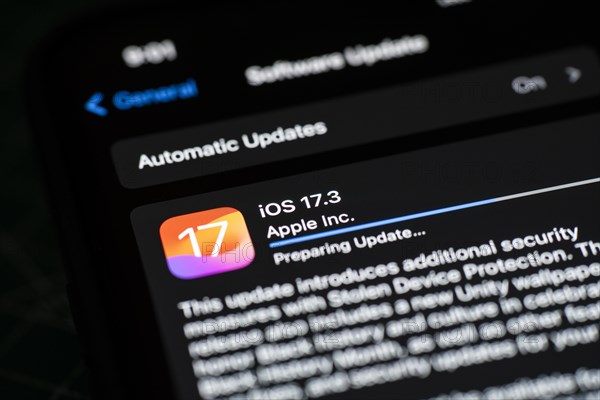 In this photo illustration a person installs updates of iOS 17.3 on an iPhone device on January 26,