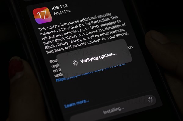In this photo illustration a person installs updates of iOS 17.3 on an iPhone device on January 26,