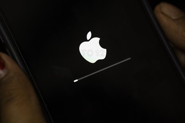 In this photo illustration a person installs updates of iOS 17.3 on an iPhone device on January 26,