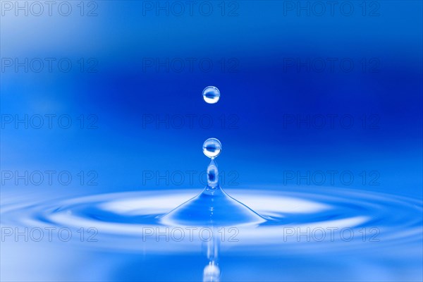 Water droplets jump up from the blue water surface