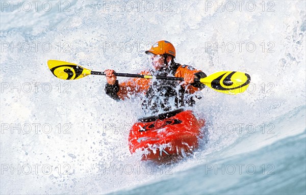 A kayaker rides in the spray in a wave in the Isar at the Wittelsbacherbrücke, Munich, Bavaria,