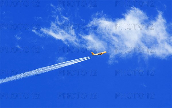 A passenger plane of the insolvent travel company Thomas Cook with vapour trails in the blue sky