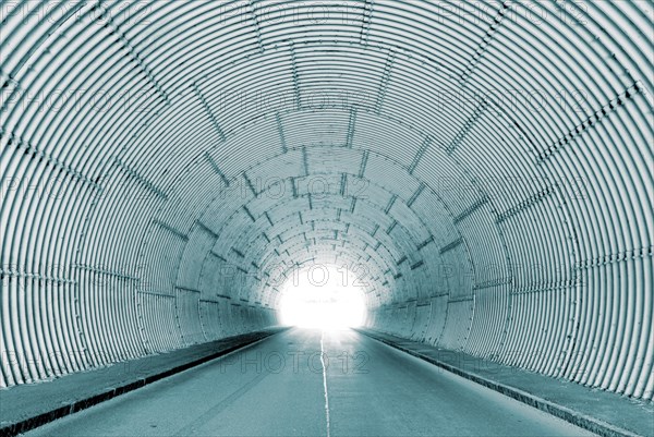 Interior view of a tunnel with bright tunnel exit, light at the end of the tunnel