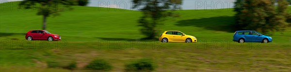 A blue, yellow and red car driving through a green landscape near Bad Kohlgrub, Bavaria, Germany,