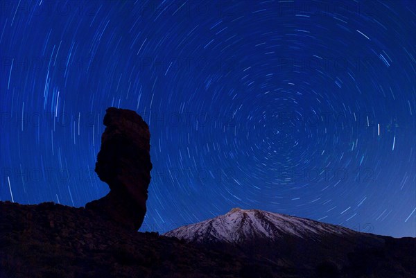 The Roque Cinchado at night with circling stars in the clear night sky and the summit of Pico de