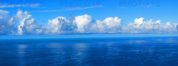 View over the blue Atlantic Ocean with white clouds, panoramic shot, from the mountain slopes near