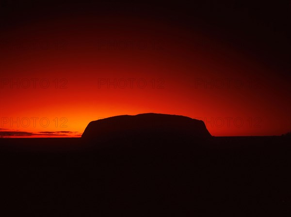 Silhouette outline of Ayers Rock or Uluru in red sunrise or sunset, dusk or dawn, red sky, Northern
