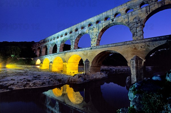 Pont du Gard in the evening light, illuminated yellow with spotlights because of an interview about