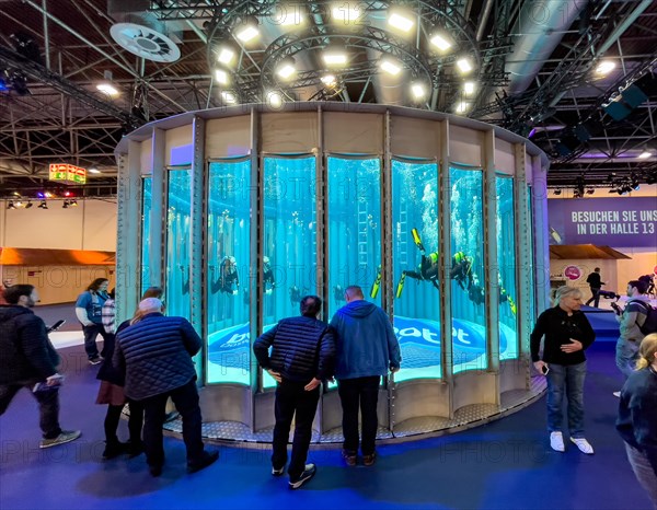 Full frontal view long shot of several divers in the water in a circular diving tower at the boot