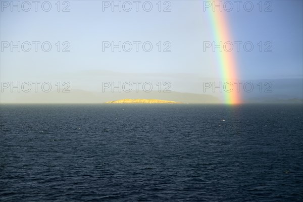 Seascape view of spectrum colours in rainbow over sea and island, Norway, Europe