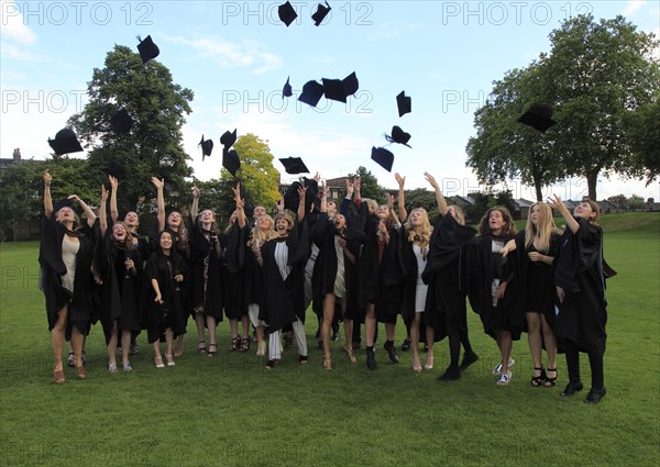 Graduates in gowns throwing their mortarboards into the air, Goldsmiths, University of London,