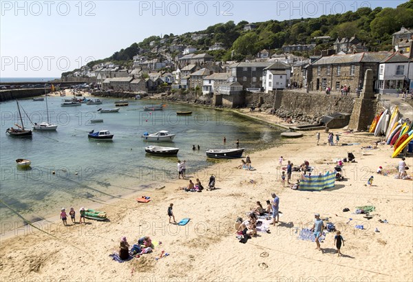 People on crowded beach in Mousehole village, Cornwall, England, UK