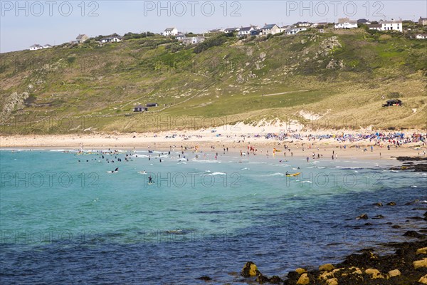 Coastal scenery with busy crowded sandy beach, Sennan Cove, Land's End, Cornwall, England, UK
